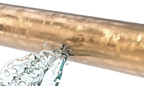 Close-up of a burst pipe spraying water, showcasing emergency plumbing services.